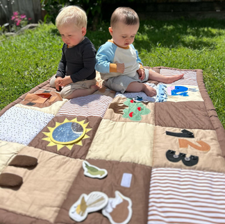 two babies on play mat outside in nature