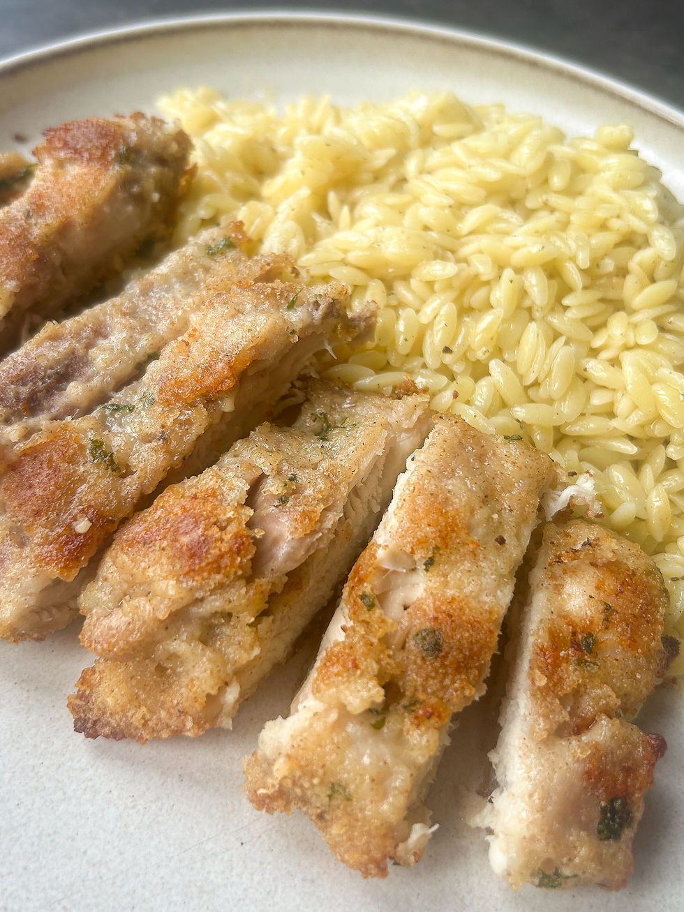 Sliced garlicky Parmesan chicken thighs served with creamy orzo pasta.