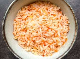 A bowl of Turkish tomato rice (domatesli pilav) with fluffy, glistening grains lightly coated in fresh tomato.