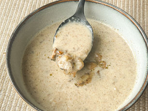Creamy mushroom soup served in a bowl with a spoon lifting sautéed mushrooms for texture and garnish.