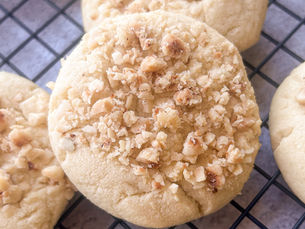 Homemade hazelnut butter cookies topped with chopped hazelnuts cooling on a wire rack.