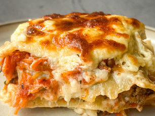 Slice of classic lasagna with homemade béchamel sauce, showing golden melted cheese on top and visible layers of meat sauce, pasta, and creamy béchamel.
