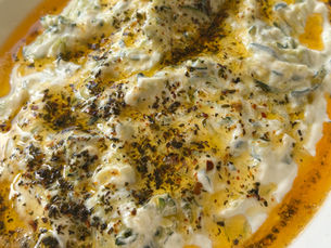 Zucchini mezze (tarator) topped with creamy garlic yogurt and drizzled with paprika butter and dried mint in a white serving dish.