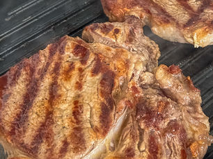 Close-up of a juicy ribeye steak being seared in a grill pan, with a crispy, golden-brown crust forming on the surface, ready for cooking to perfection.