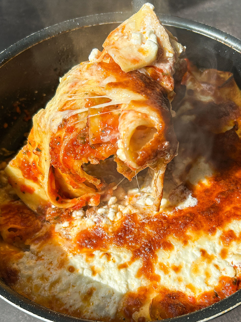 One-pan lasagna with cottage cheese served hot in a skillet, topped with golden melted mozzarella and a steaming cheese pull showing layers of pasta and rich tomato sauce.