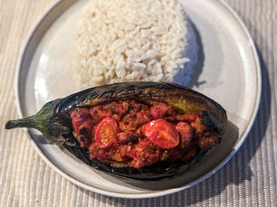 Turkish-style stuffed eggplant (karniyarik) served with a side of rice on a plate