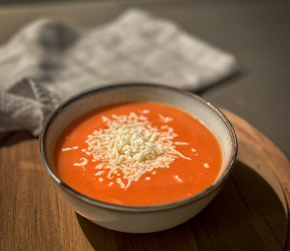 Close-up view of a bowl of tomato soup with melted cheese on top