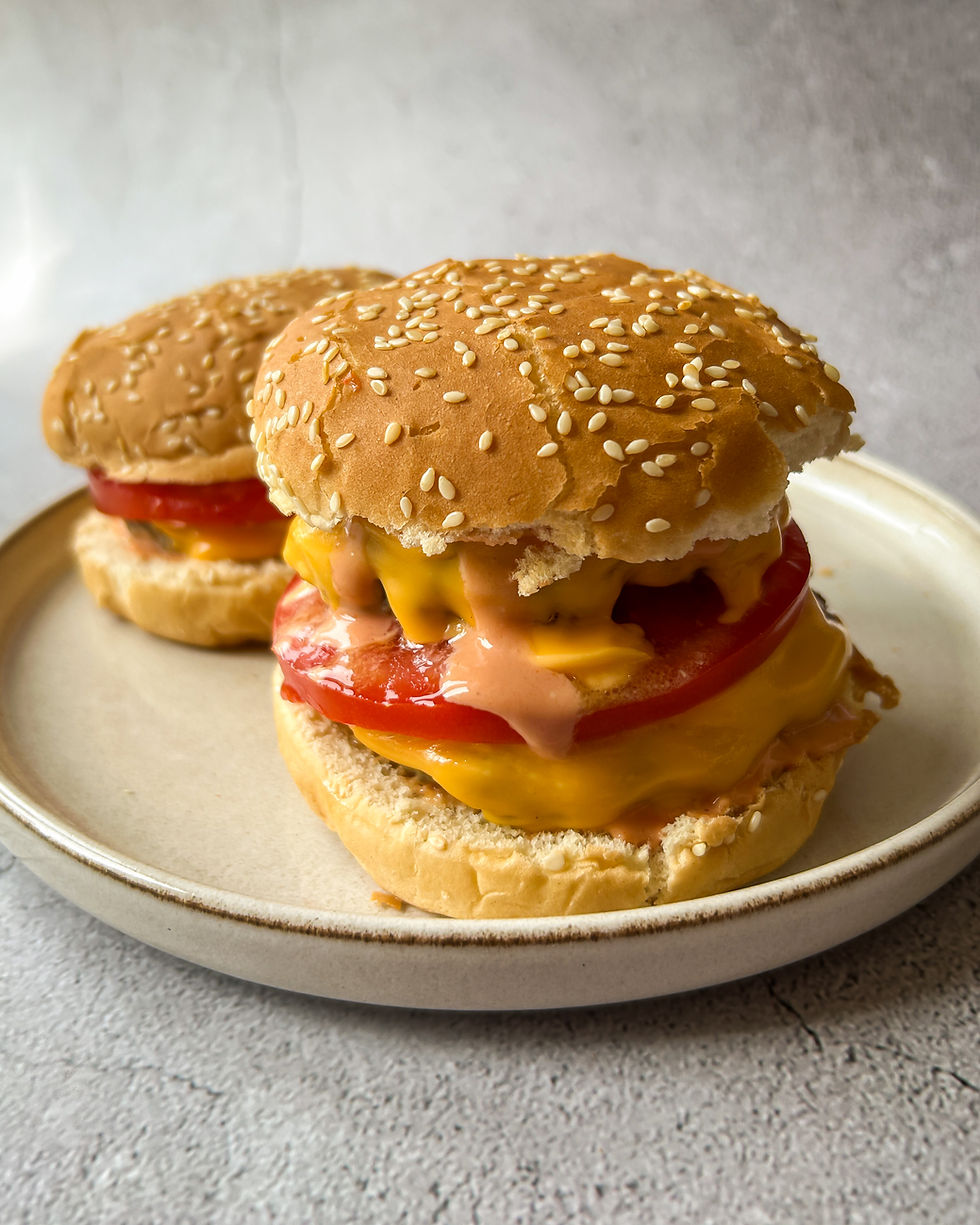 Cheddar peyniri erimiş, domates ve burger sosu ile hazırlanan sulu ev yapımı cheeseburgerler, susamlı hamburger ekmeği içinde servis ediliyor.