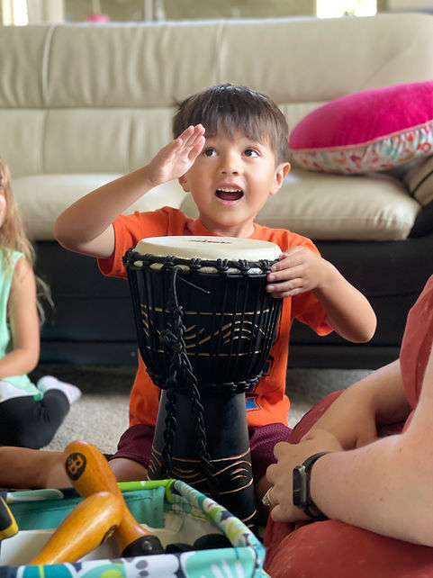 A young boy hitting a drum in a music therapy session