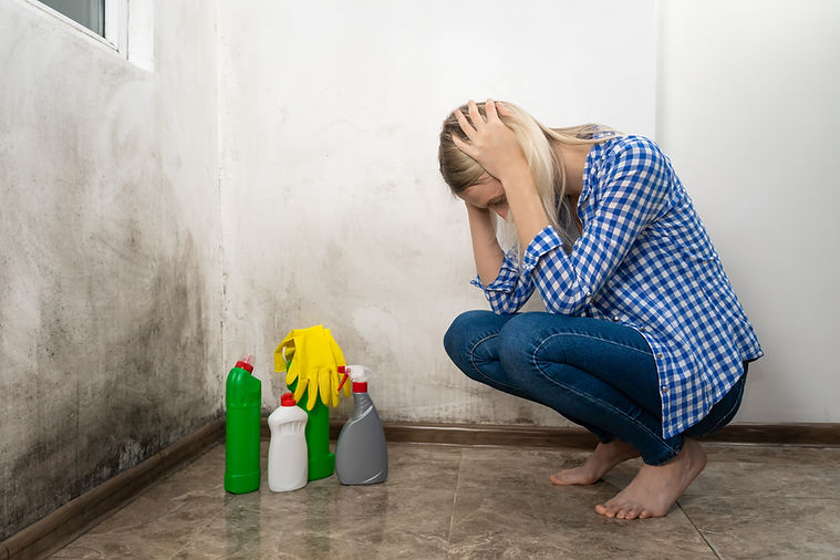 Young shocked blonde woman in blue jeans and a shirt is squatting with cleansers near a wa