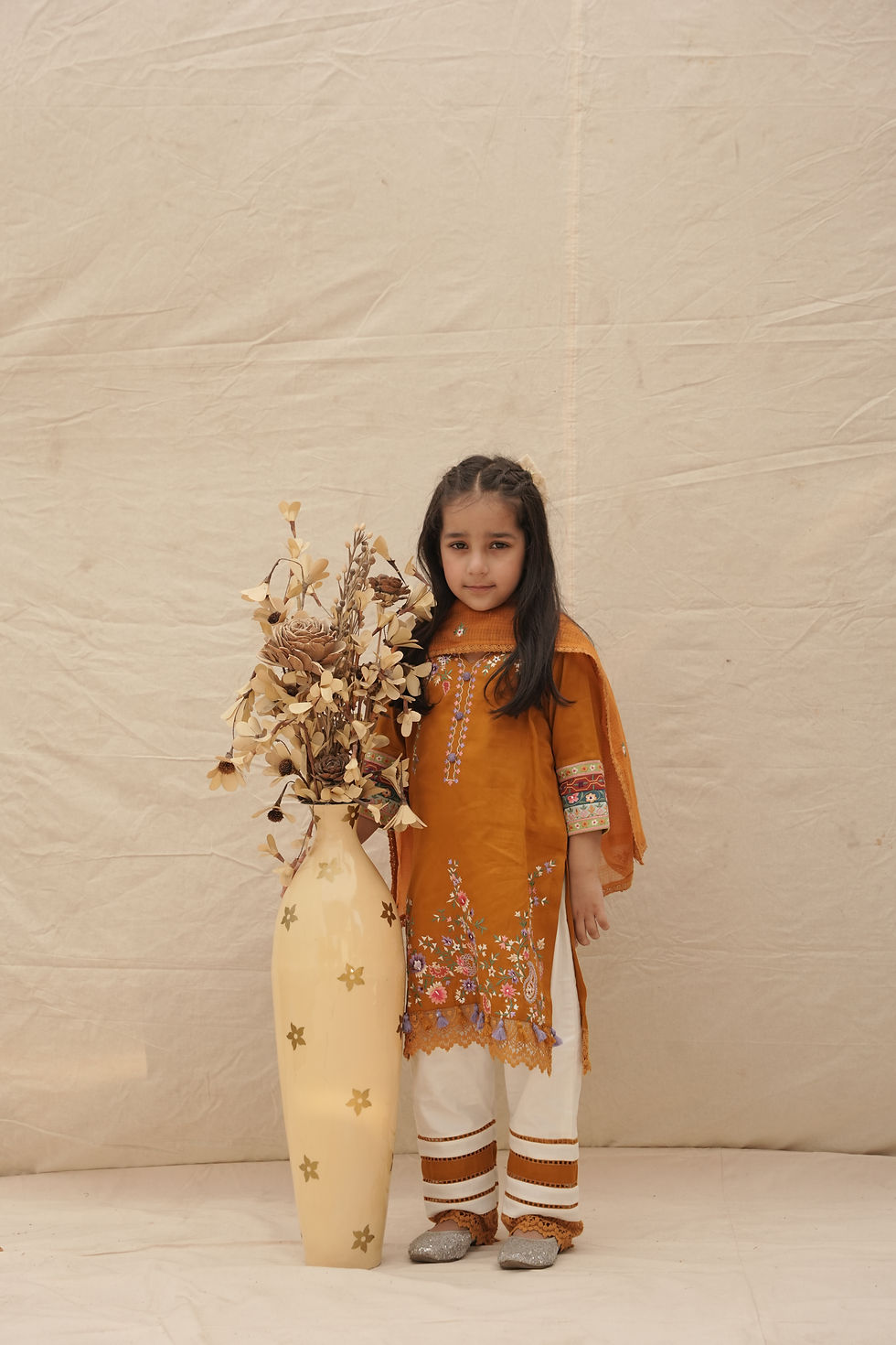 Thumbnail: shy model kid holding flowers and posing wearing 100% giza cotton kurta in mustard color with contrast/matching organza dupatta