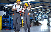 factory-workers-work-wear-yellow-helmets-walking-through-industrial-production-hall-discus