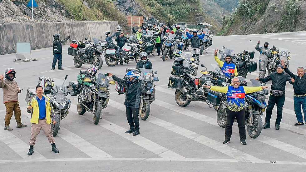 Malaysian motorcycle riders celebrate a scenic road stop during their Vietnam caravan tour, with big bikes parked along a mountainous route organized by Visit Indochina.