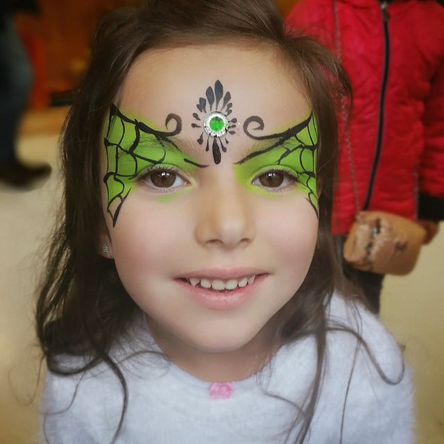 Children's Halloween face painting with purple and orange designs