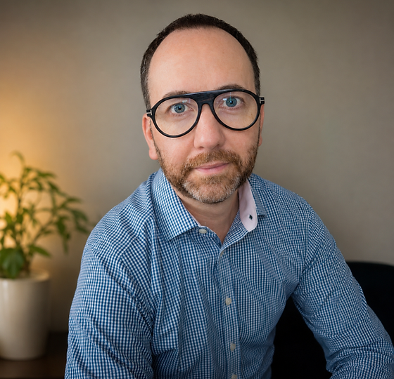 Professional headshot of Paul Madden, BACP-accredited online counsellor and therapist, smiling warmly while seated indoors in