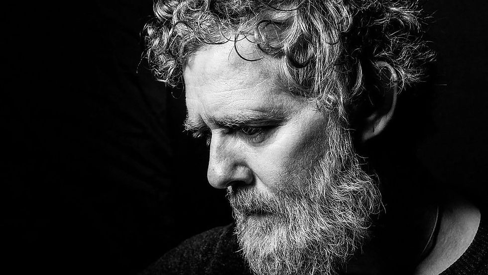 Black-and-white portrait of Irish musician Glen Hansard, captured in a reflective moment, symbolising remembrance, public grief, and the enduring impact of his music and legacy.