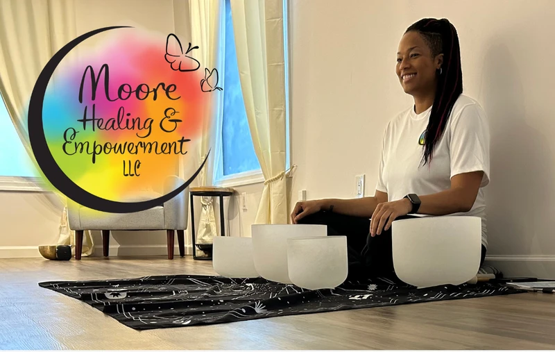 Woman sitting with singining bowls smiling, with the business logo on the picture