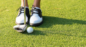 Golfer wearing white golf shoes.