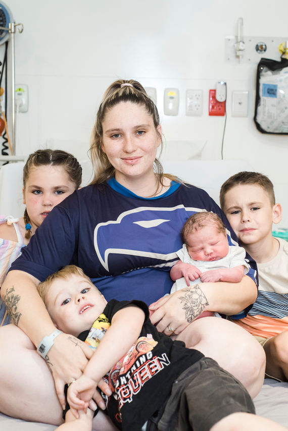 new-mum-holding-baby-boy-with-two-older-brothers-and-older-sister-cuddled-up-on-hospital-bed-perth-fresh-48-and-newborn-photographer
