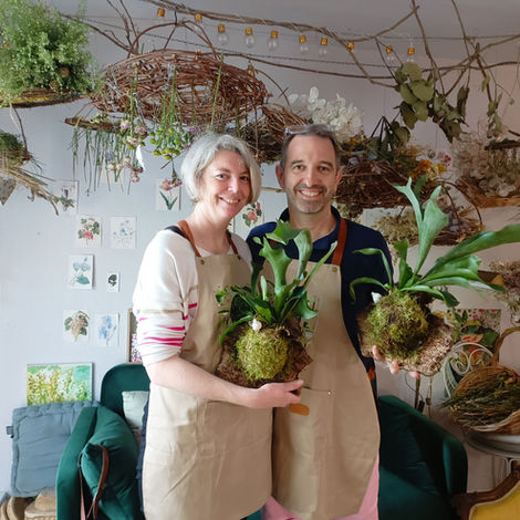 Deux personnes souriantes tenant des kokedamas Corne d'Élan.