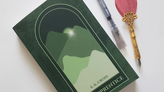 book of the apprentice on a white surface background with a pen and quill beside it.