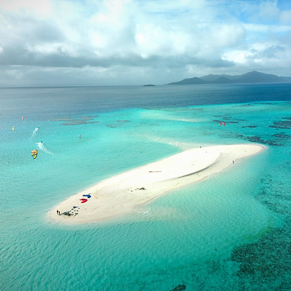 People kitesurfing around a sand island off the coast of Fiji