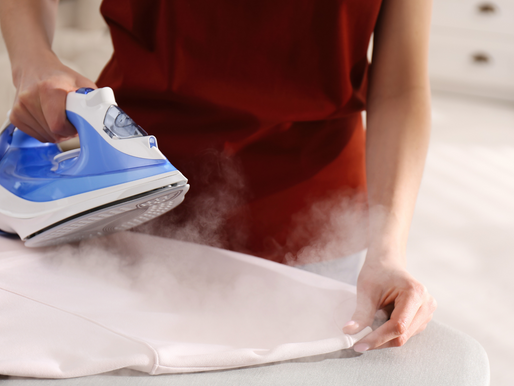A woman ironing a red button-down shirt