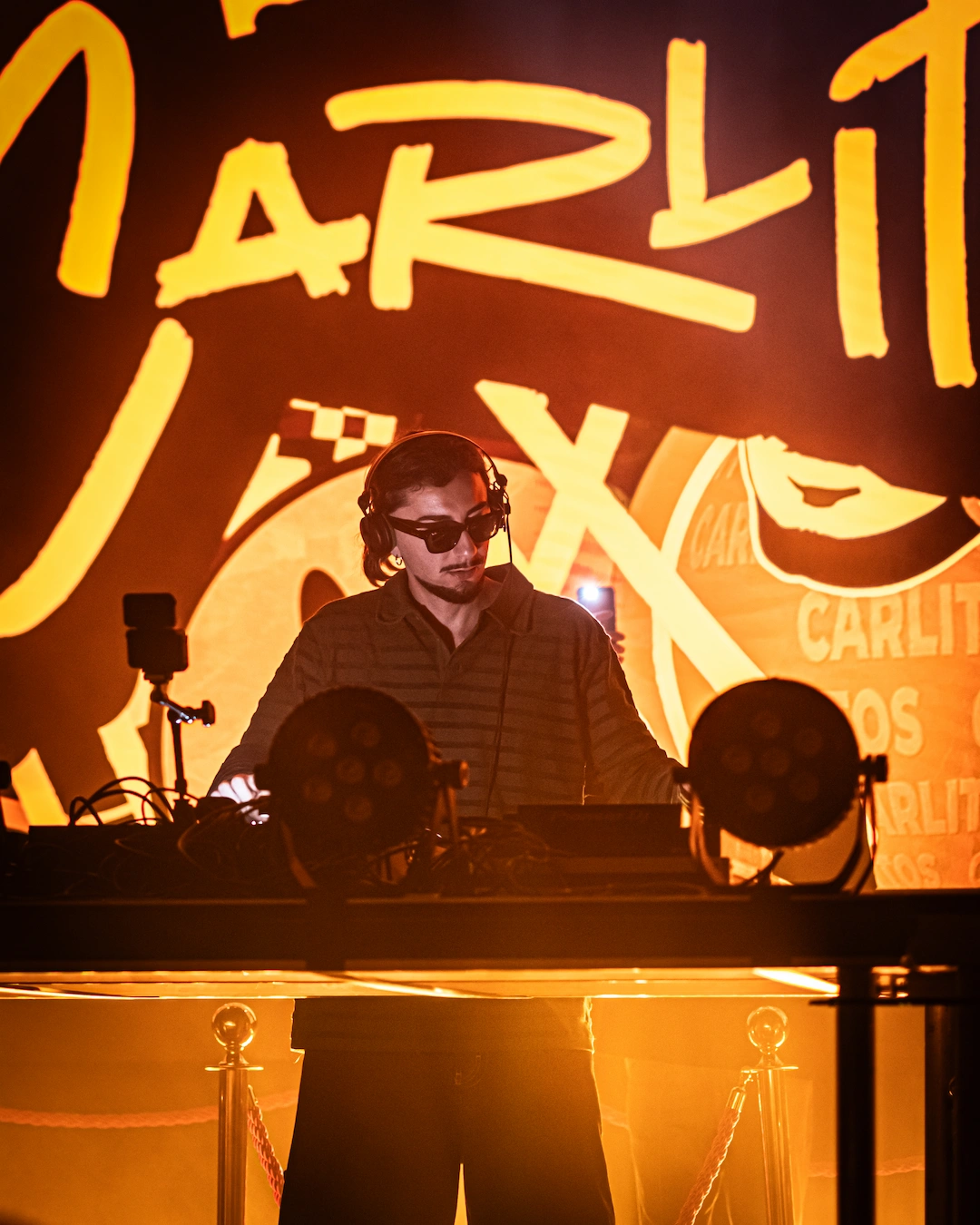 DJ performing on stage at a ParisLatino event, surrounded by warm lighting and branded visuals, creating an immersive club atmosphere.