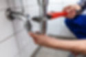 Plumber fixing a leaking pipe with a wrench, Plumbing Services, Iverson Plumbing.