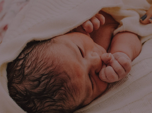 a newborn baby us cuddled up in a white blankert