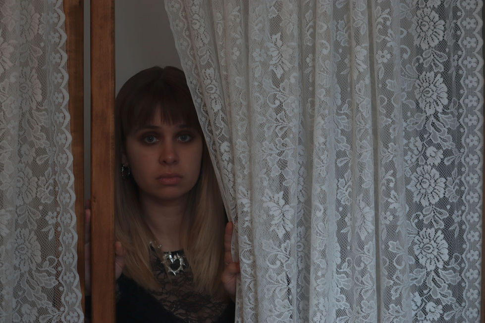 woman peeking through curtains