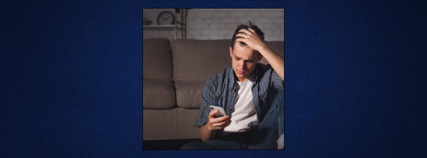 Worried teen boy looking at phone