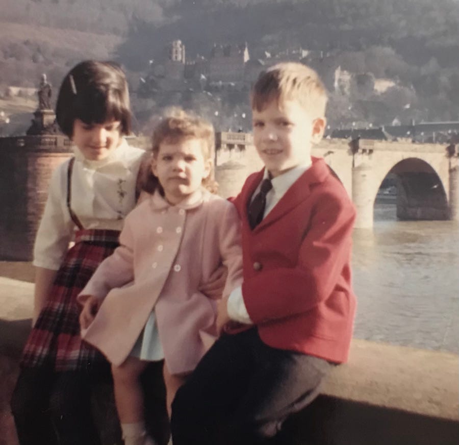 Lynne, Cynthia and Anthony Jr. Carbone sitting along the Necker River in Heidelberg, West Germany in the early 1960s. The Alte Brücke (Old Bridge) and der Heidelberg Schloss (Heidelberg Castle) can be seen in the background.