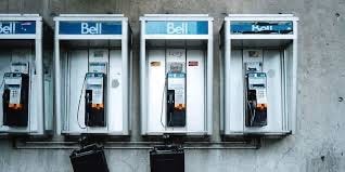 Photograph of 4 Old Bell Telephone pay phone on a wall.  Biography of Dr. Anthony J. Carbone.