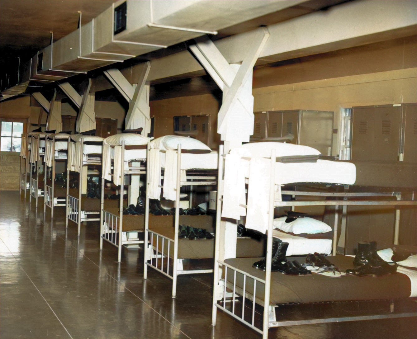 Interior view of a typical World War II Army barracks, Line of bunk beds with olive drab Army blankets and boots on bed.   Found on Camp Forsyth for Army ROTC Advanced Camp.  Biography of Dr. Anthony J. Carbone