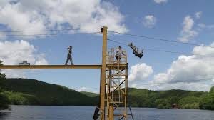 U.S. Army cadet at Recondo water obstacle area.  Balancing on beam over water, with Recondo sign hanging from beam.  Another cadet hanging from a rope. Biography of Dr. Anthony J. Carbone.