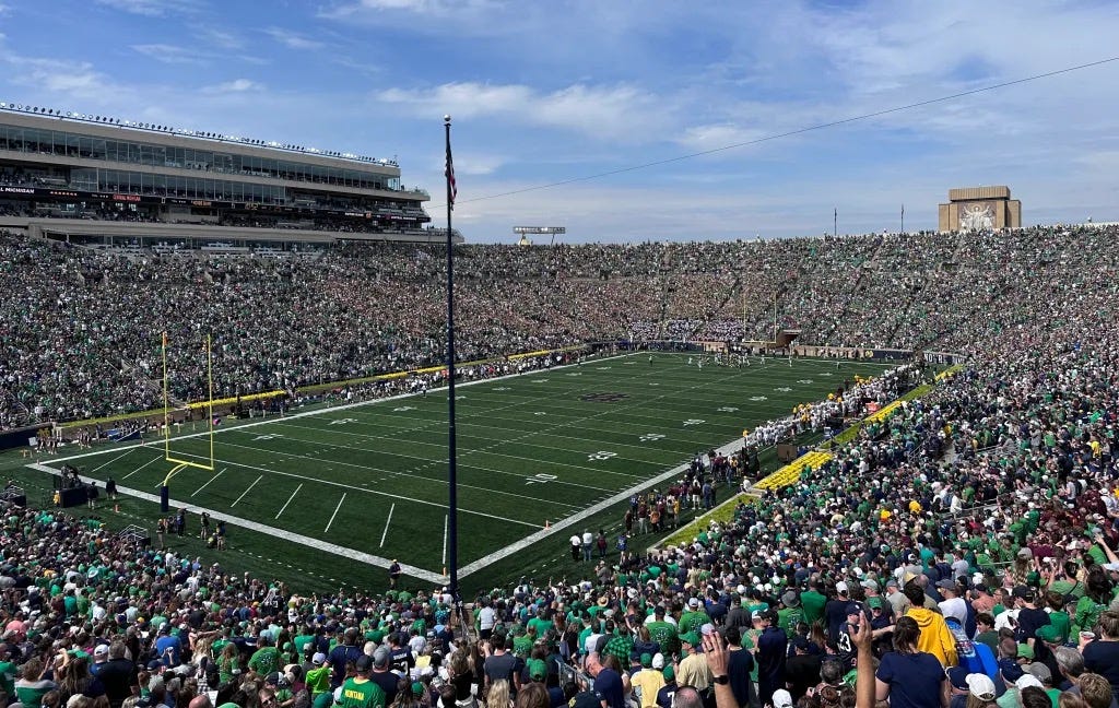 Notre Dame Stadium on Fighting Irish Football Game Day. Stands are packed with tens of thousands of students and fans. The libray with the mural of “Touchdown Jesus” can be seen in the distance. Autobiography of Dr. Anthony J. Carbone.