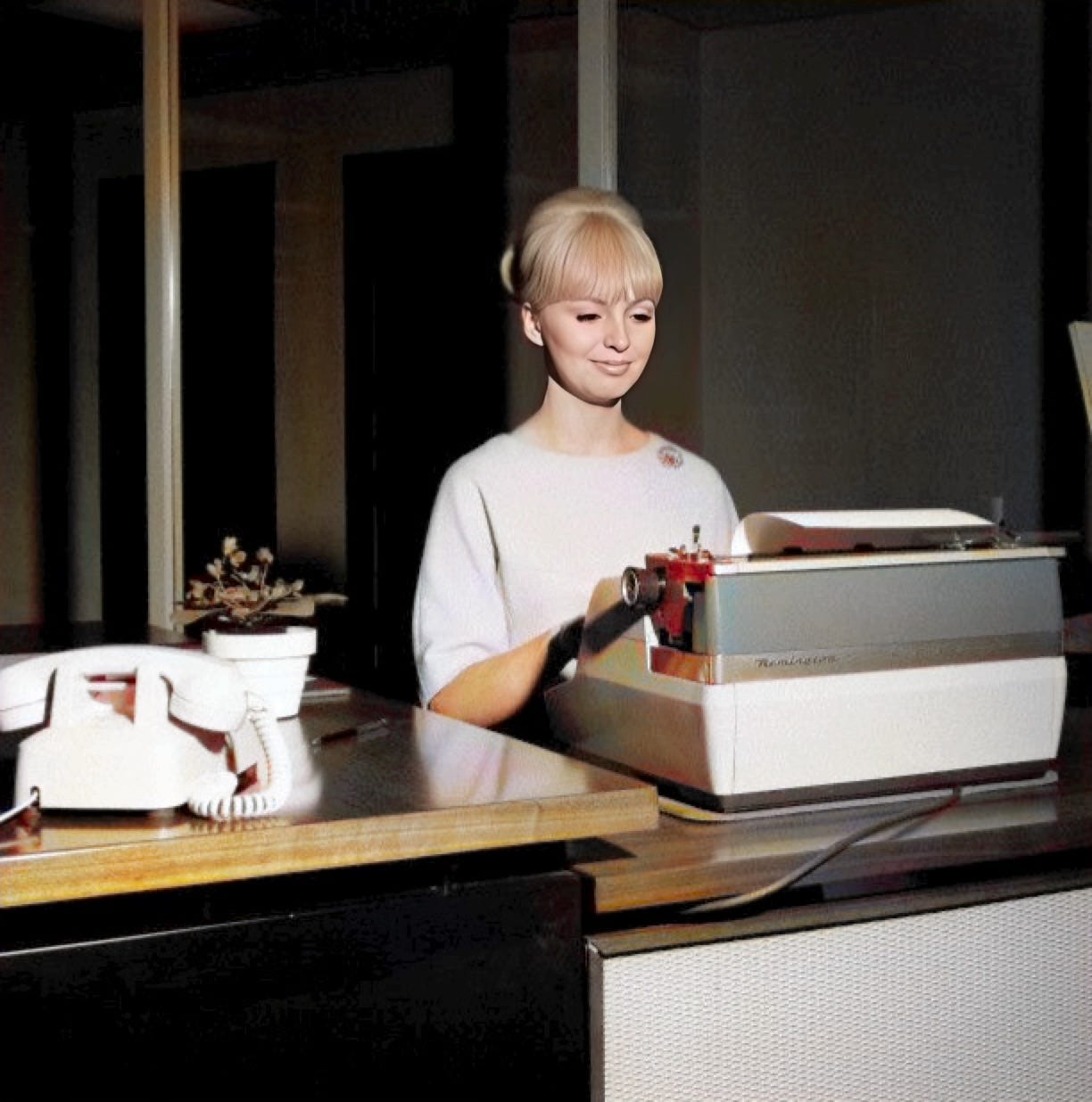 Photograph of blonde woman typing on an old electric typewriter at an office desk.  Autobiography of Dr. Anthony J. Carbone.