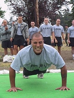 Photograph of an Army ROTC cadet doing pushups while a group of cadets watch.  Autobiography of Dr. Anthony J. Carbone.