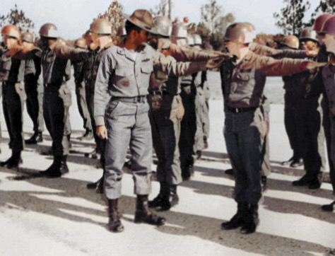 U.S. Army platoon in formation for inspection. Dress-Right-Dress command. Soldiers in olive drab fatigues with helmuts. Autobiography of Dr. Anthony J. Carbone.