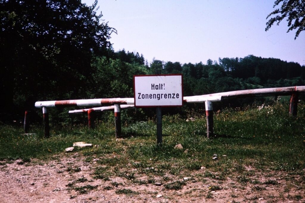 Photograph showing the West-East German border at the Fulda Gap with barricade with sign saying "Halt! Zonengrenze" (Stop! Border).  Autobiography of Dr. Anthony J. Carbone.