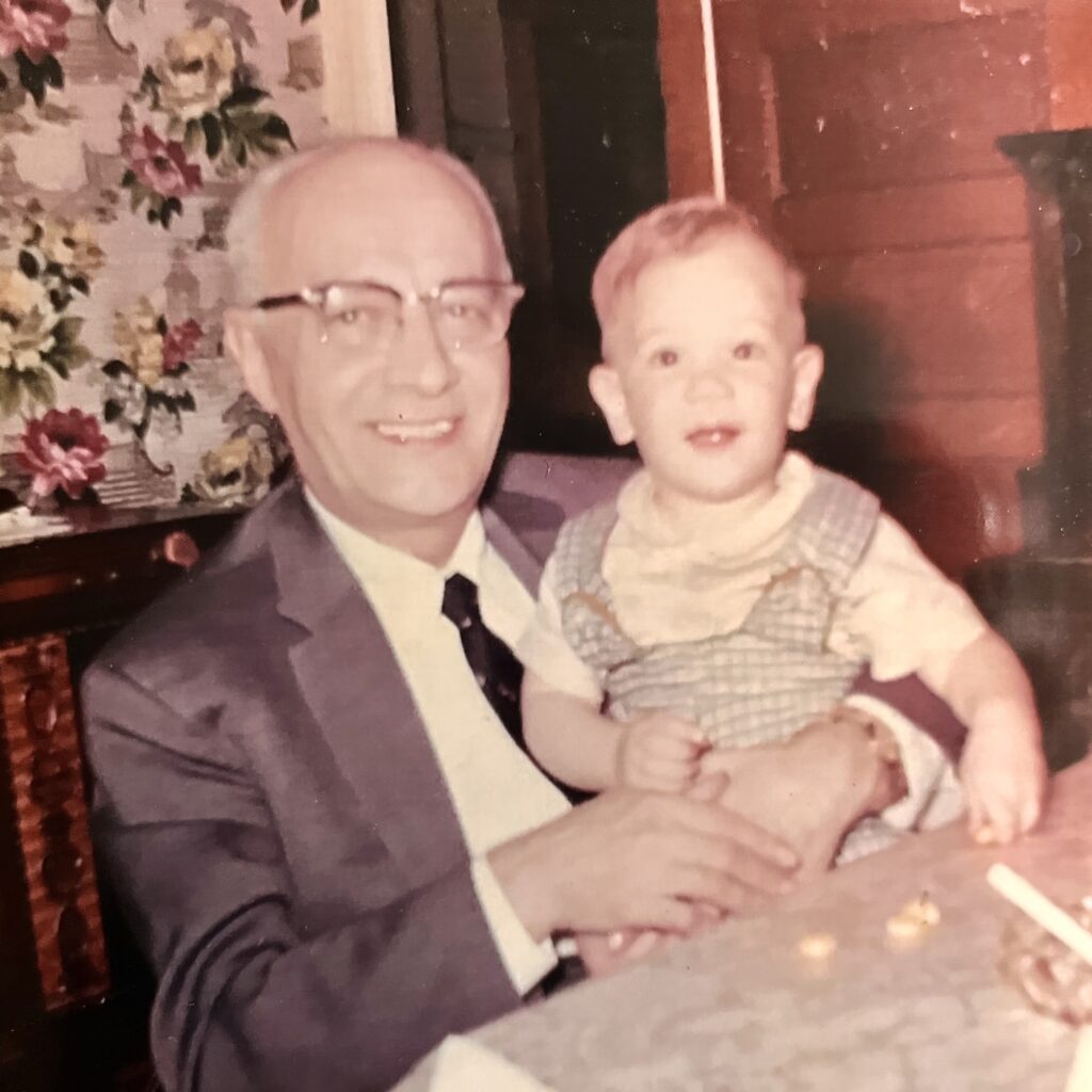 Photograph of my grandfather, Papa Carbone (Anthony Benjamin Carbone the tailor) holding me when I was about one year old.  Gray haired gentleman wearing a suit and tie holding a toddler boy in his arms.  Autobiography of Dr. Anthony J. Carbone.