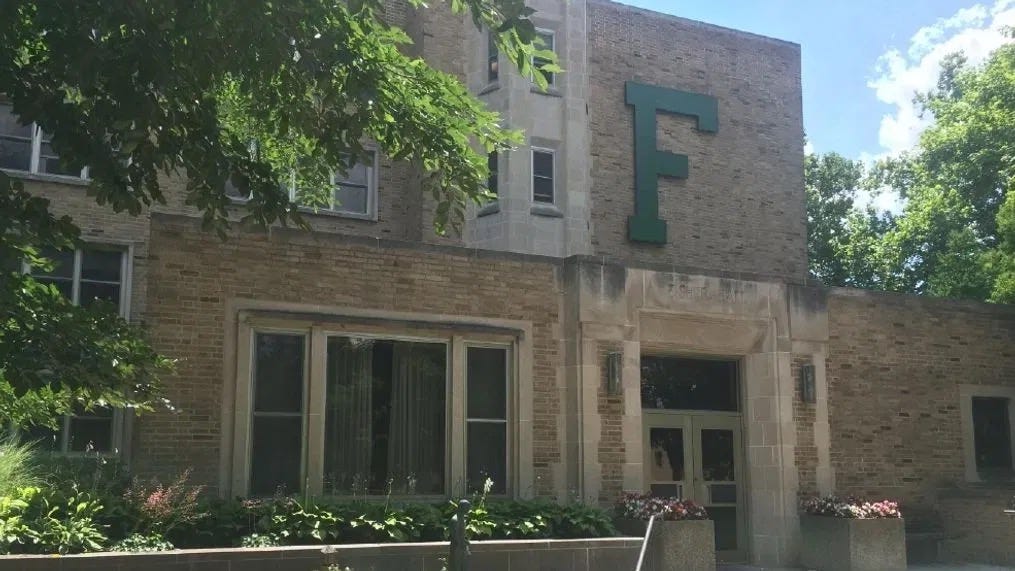 Photograph of Fisher Hall in the South Quad of the University of Notre Dame with its classic tan bricks and large green "F" for "Fisher".  Autobiography of Dr. Anthony J. Carbone.