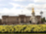 A landscape image of Buckingham Palace, showing the huge building, statue, and green space