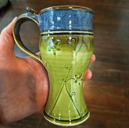 Wheel-thrown stoneware mug with hand-stamped pattern in moss green glaze, handmade functional pottery from Plays In Mud pottery studio in West Asheville NC.