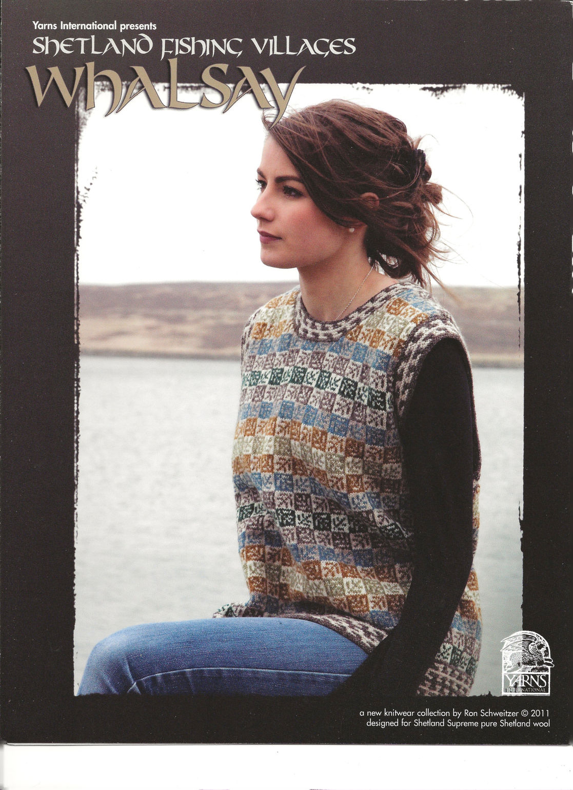 A woman sits by the water wearing a a stranded colorwork vest.