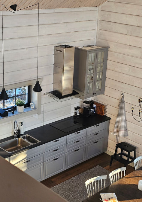 Kök med grå skåp och bänkskiva. Fönster, lampor och Fjällstugebyggarna