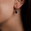 Thumbnail: Close up of model wearing garnet teardrop earrings.
