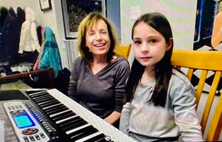 Mom and middle school girl smile during their online piano lesson