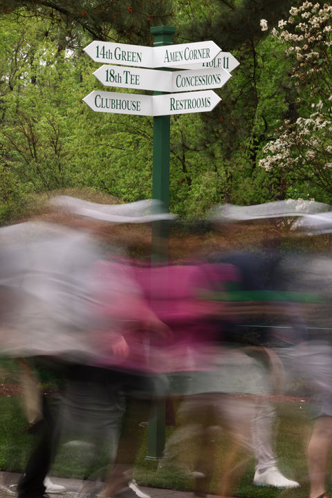 a long exposure picture of patrons walking past the Amen Corner sign at the masters in augusta